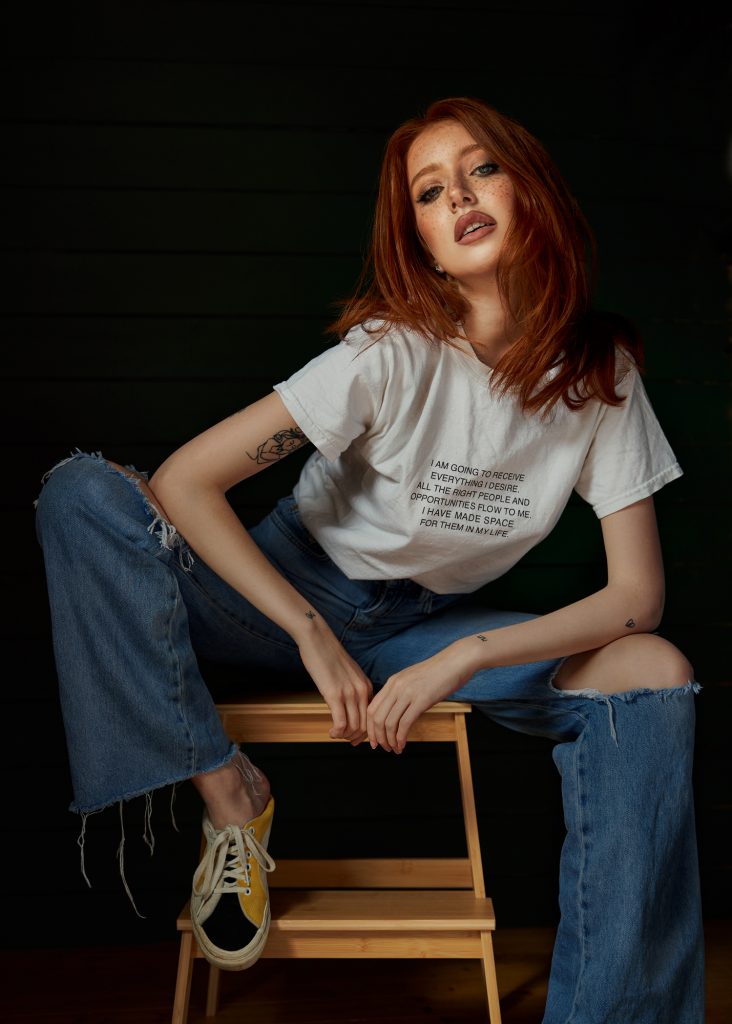 A portrait of a female model sat on a stool